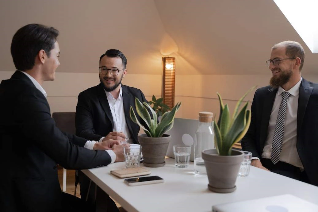 A group of men in black suit sitting near the table while having conversation.