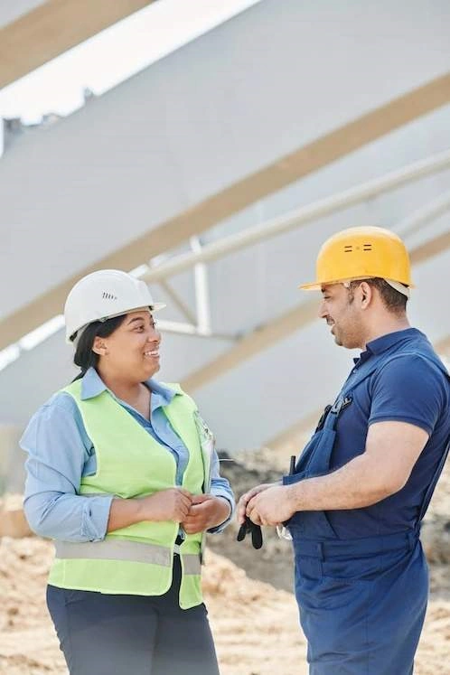 Man, woman wearing hardhats converse.