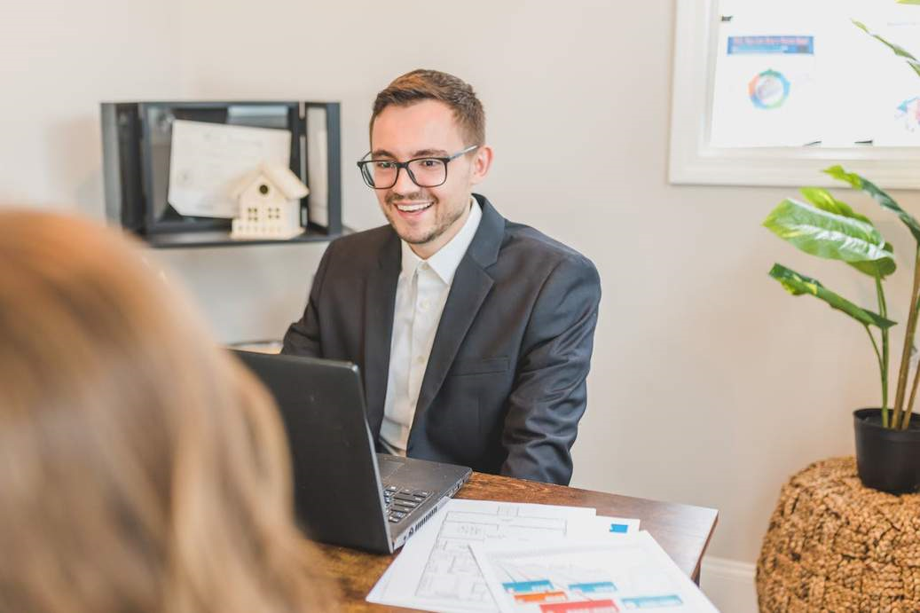 A broker smiling behind his office desk